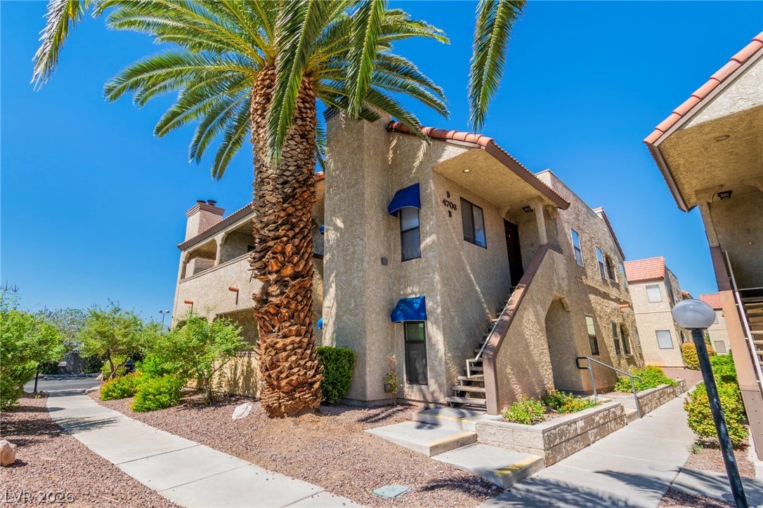 Spanish tile roofs and stucco exteriors define this multi-level residential complex framed by palm trees.