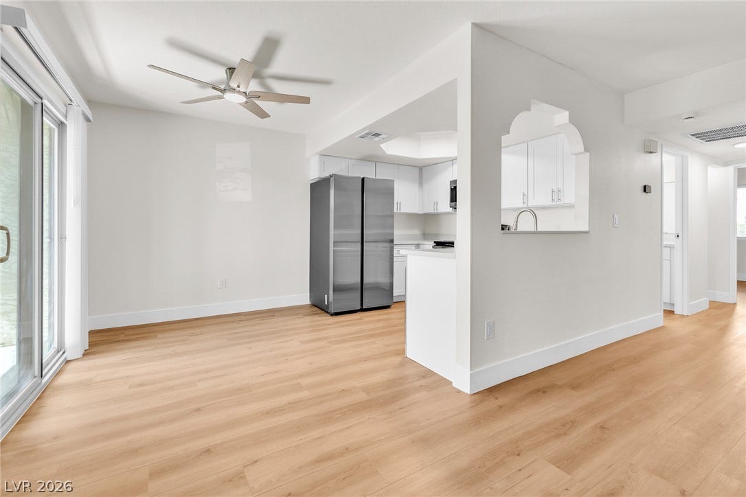 Warm wood flooring flows seamlessly through this open-concept layout leading toward the kitchen area.