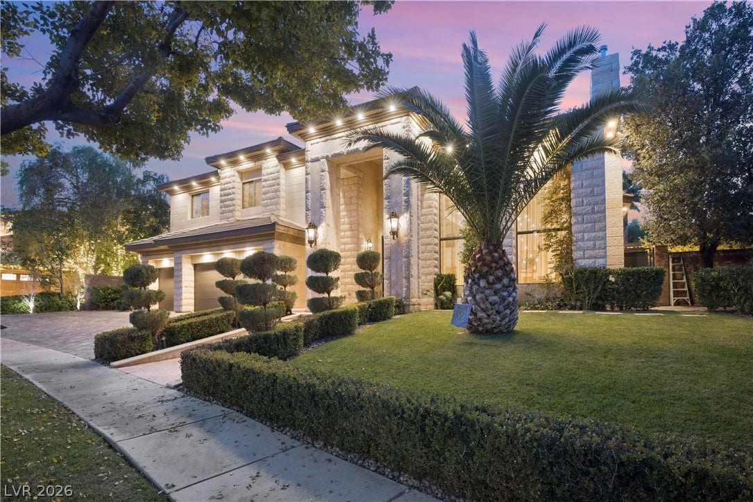 9624 Grand Isle Lane, Las Vegas, NV 89144 Dramatic architectural lighting illuminates the textured stone facade and manicured landscape at dusk.