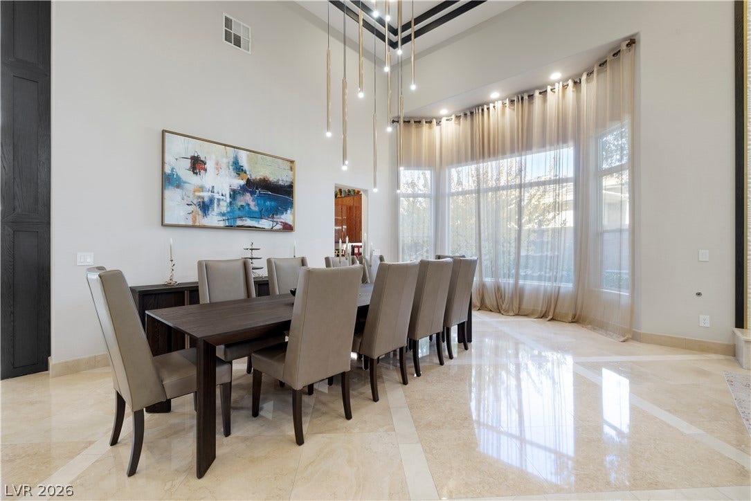 9624 Grand Isle Lane, Las Vegas, NV 89144 Polished tile flooring and soaring ceilings with a curved window wall elevate this dining area.