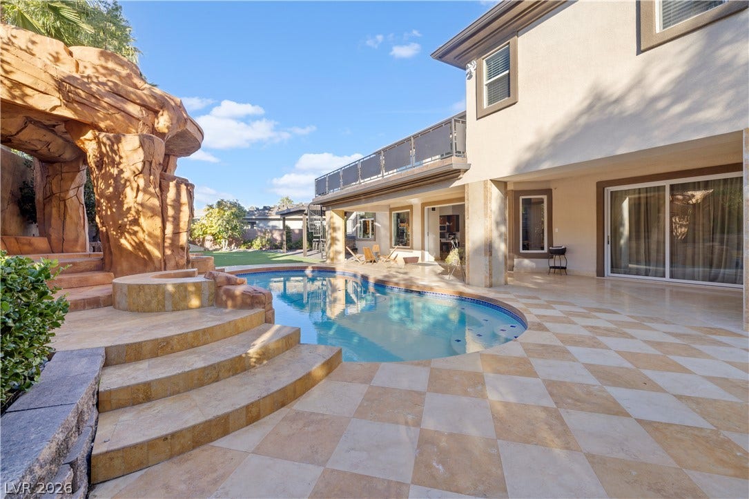 9624 Grand Isle Lane, Las Vegas, NV 89144 An inviting backyard oasis features a custom swimming pool framed by elegant tiled decking.