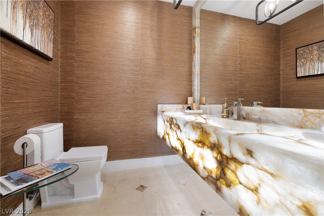 9624 Grand Isle Lane, Las Vegas, NV 89144 Textured wall coverings complement a dramatic backlit stone vanity in this modern powder room.