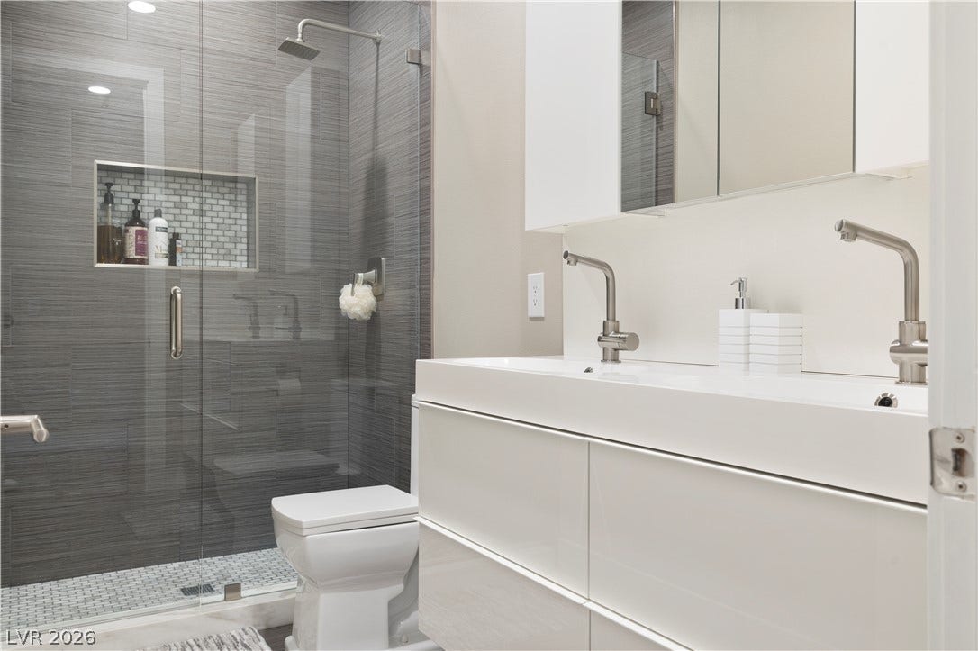 9624 Grand Isle Lane, Las Vegas, NV 89144 A contemporary bathroom features a glass-enclosed walk-in tile shower and modern double vanity.