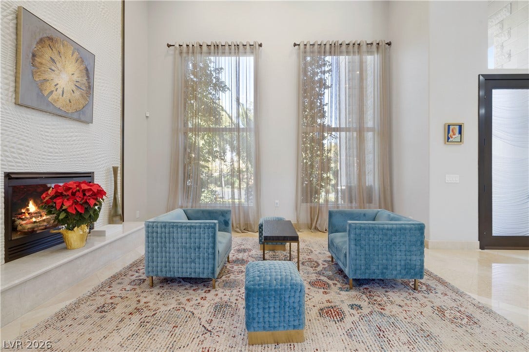 9624 Grand Isle Lane, Las Vegas, NV 89144 Towering ceilings and soaring windows frame a warm fireplace in this elegant living room.