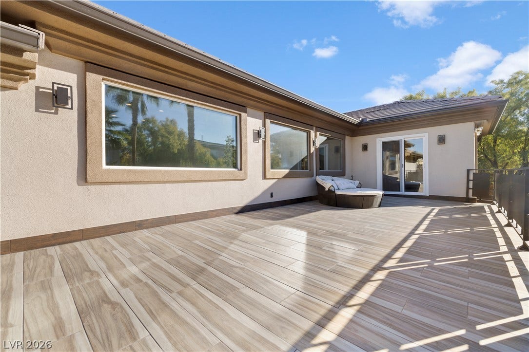 9624 Grand Isle Lane, Las Vegas, NV 89144 An expansive upper-level tiled terrace features sleek glass sliding doors and large picture windows.