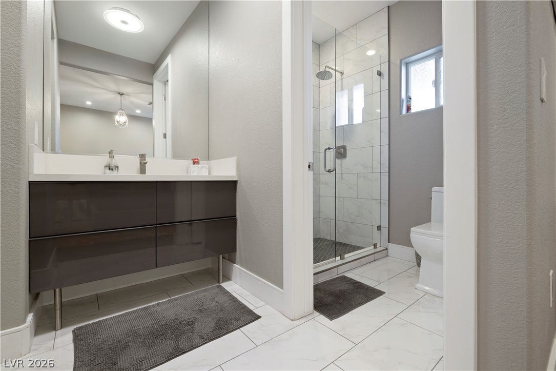 9624 Grand Isle Lane, Las Vegas, NV 89144 Modern tile flooring pairs with a glass-enclosed walk-in shower in this updated bathroom.
