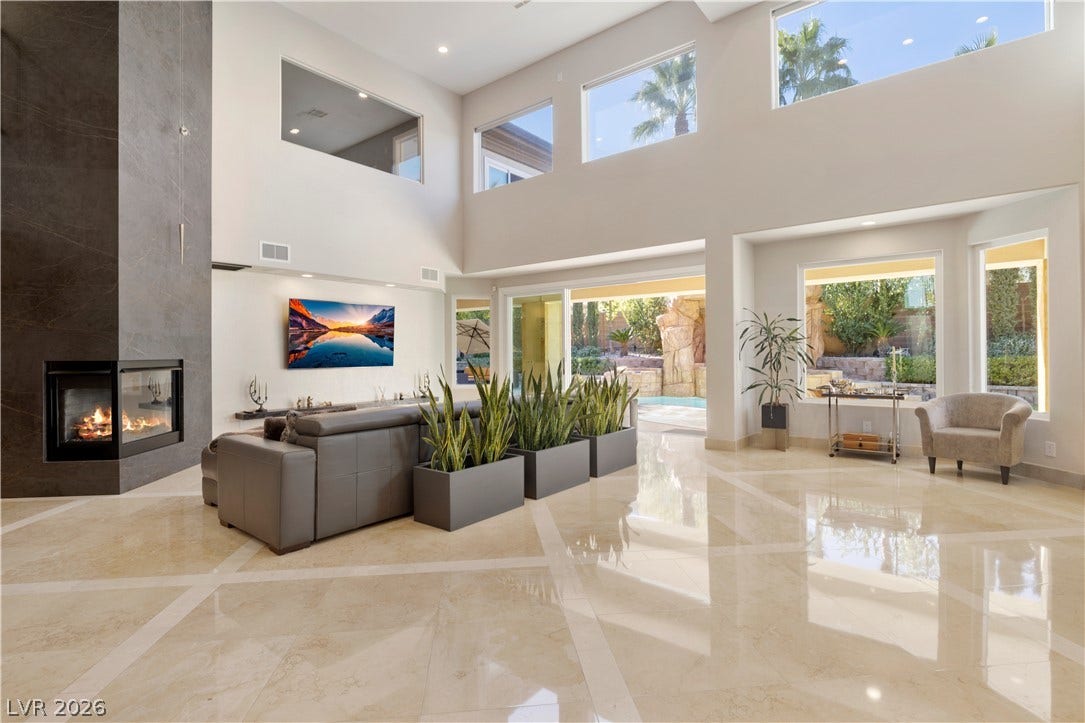 9624 Grand Isle Lane, Las Vegas, NV 89144 Gleaming polished tile floors reflect light in this double-height living room with an integrated fireplace.