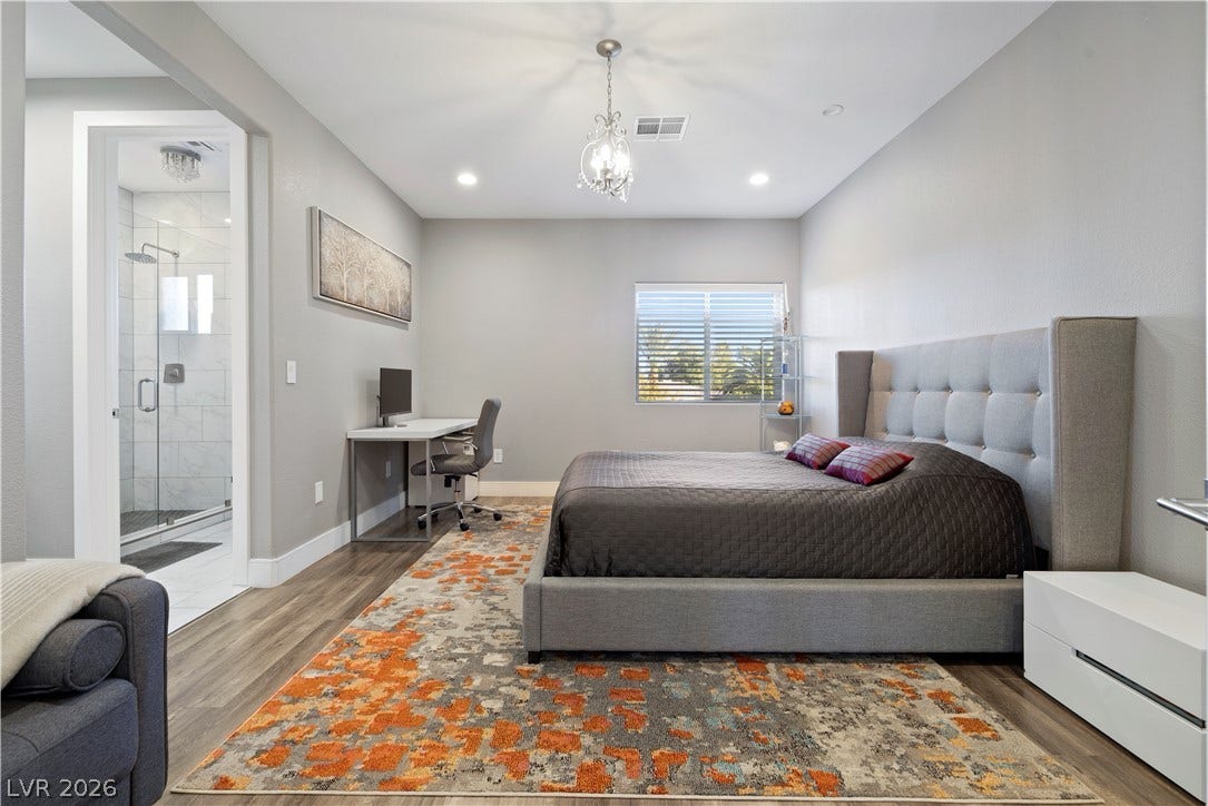 9624 Grand Isle Lane, Las Vegas, NV 89144 Rich wood-inspired floors and recessed lighting enhance this modern bedroom suite with an attached bath.