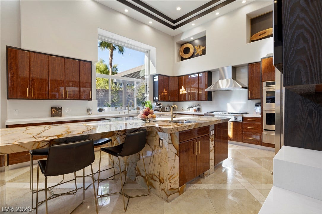 9624 Grand Isle Lane, Las Vegas, NV 89144 Dramatic high ceilings and a custom stone waterfall island define this gourmet kitchen space.