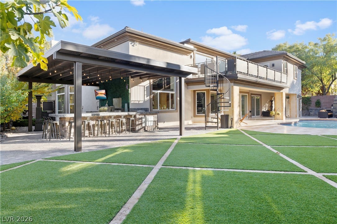 9624 Grand Isle Lane, Las Vegas, NV 89144 Geometric turf details accent the sprawling backyard retreat featuring a pool and outdoor kitchen.