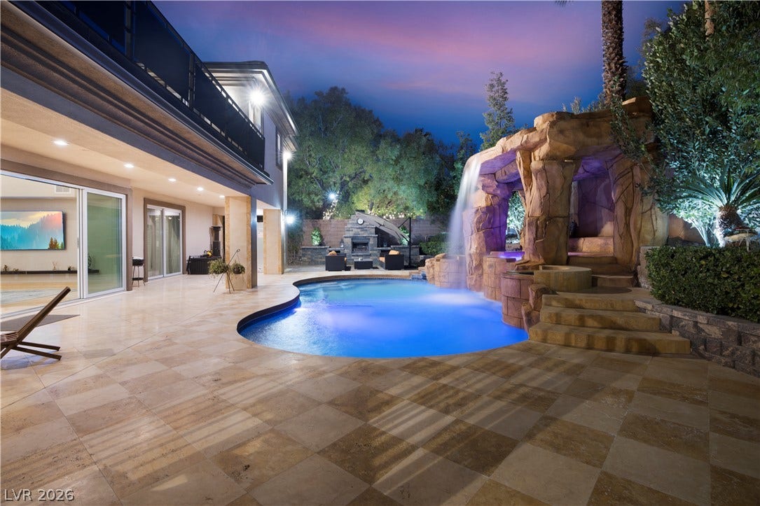 9624 Grand Isle Lane, Las Vegas, NV 89144 A resort-style swimming pool features a custom stone waterfall, spa, and expansive tiled patio.