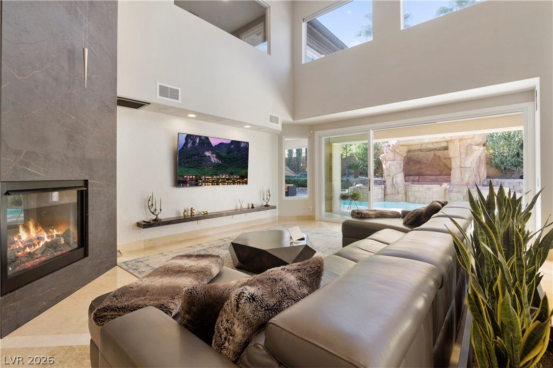 9624 Grand Isle Lane, Las Vegas, NV 89144 A striking fireplace accent wall highlights the soaring ceilings and sliding doors in this space.