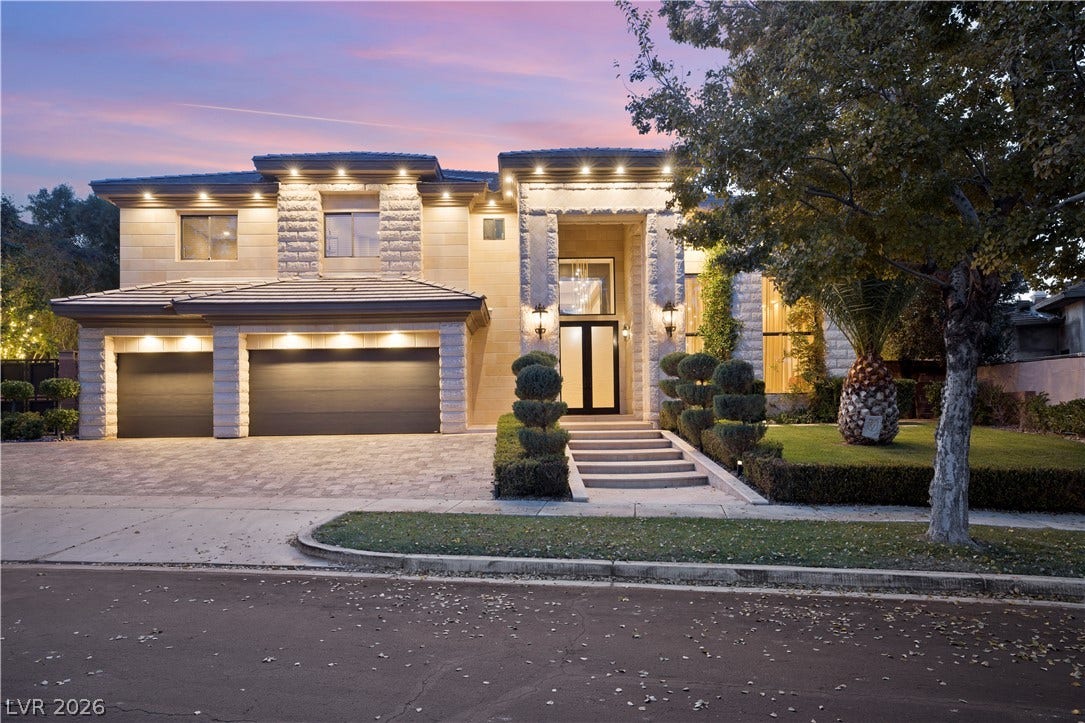 9624 Grand Isle Lane, Las Vegas, NV 89144 Dramatic exterior lighting illuminates the stone facade and paved driveway of this two-story estate.