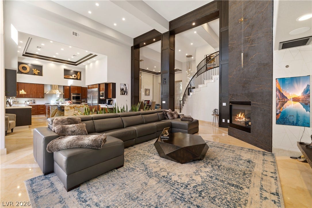 9624 Grand Isle Lane, Las Vegas, NV 89144 Soaring ceilings and a floor-to-ceiling stone fireplace anchor this grand, open-concept living space.