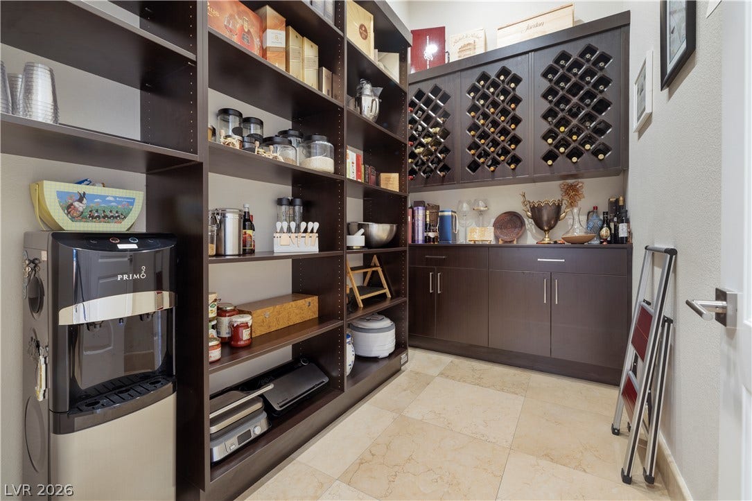 9624 Grand Isle Lane, Las Vegas, NV 89144 A well-organized walk-in pantry boasts abundant dark wood shelving, custom cabinetry, and tiled flooring.