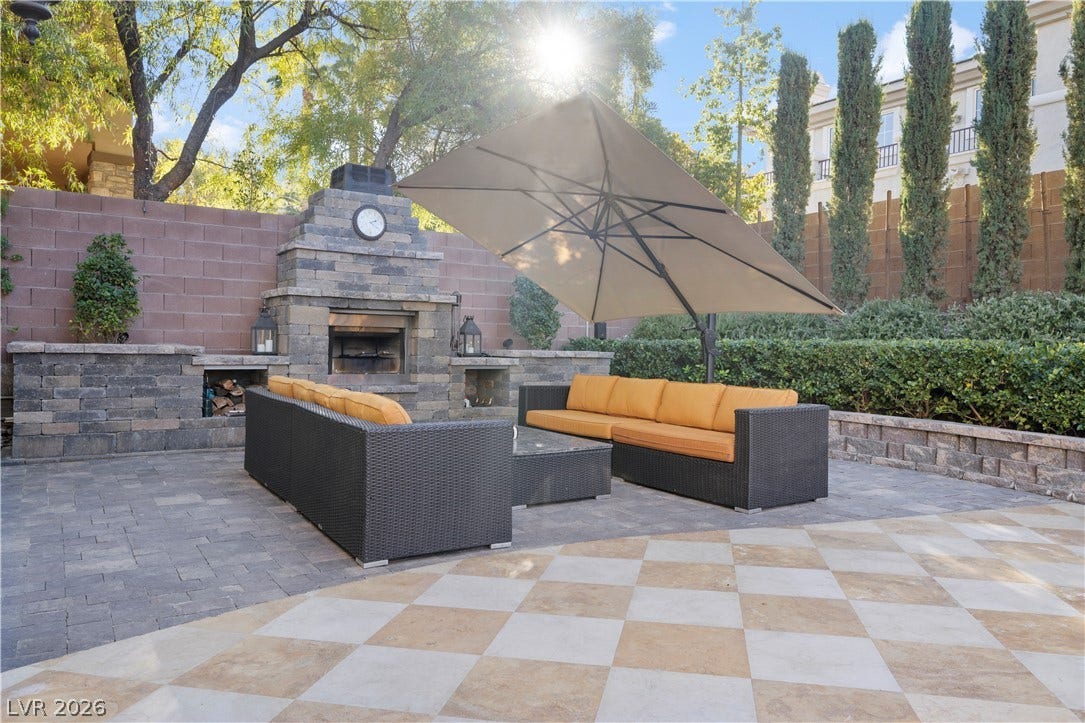 9624 Grand Isle Lane, Las Vegas, NV 89144 An inviting stone fireplace anchors the spacious stone paved patio surrounded by mature trees.