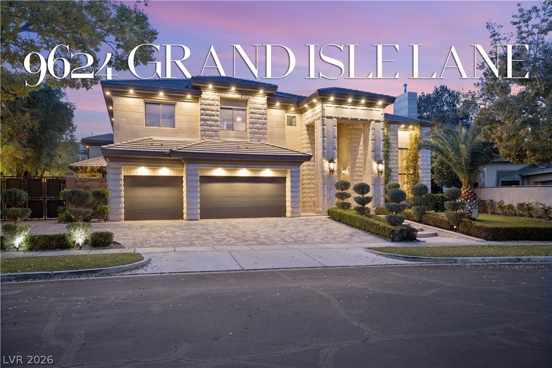 9624 Grand Isle Lane, Las Vegas, NV 89144 Dramatic exterior lighting illuminates the stone facade and paved driveway of this two-story estate.