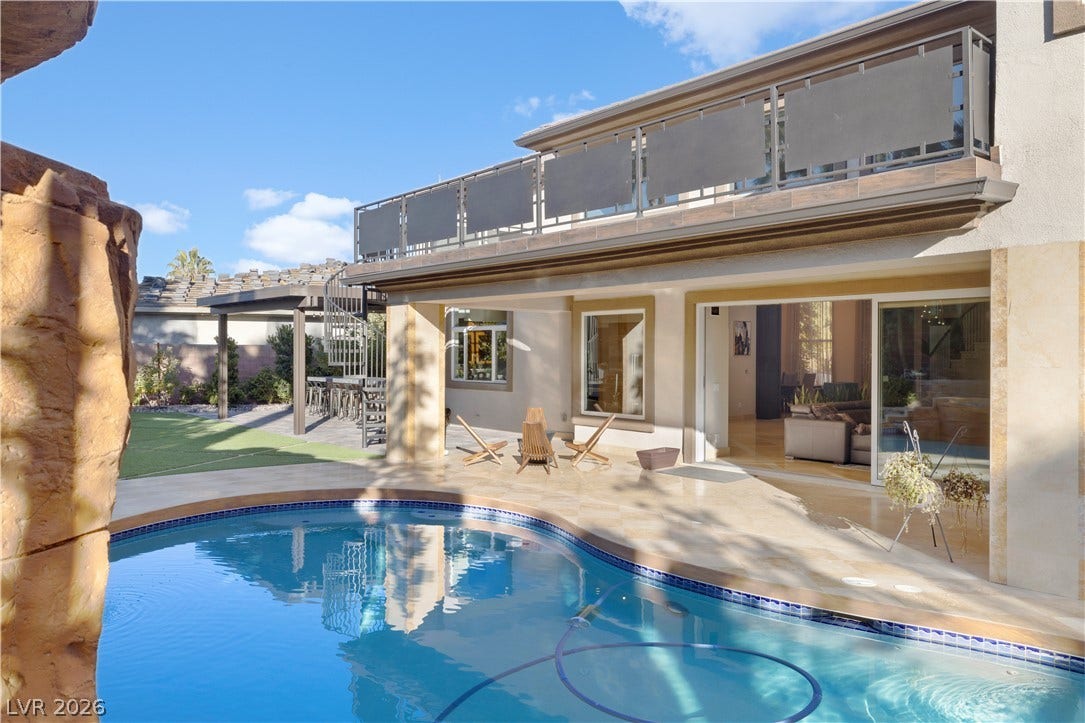 9624 Grand Isle Lane, Las Vegas, NV 89144 An inviting backyard oasis features a custom-shaped swimming pool alongside stone patio decking.