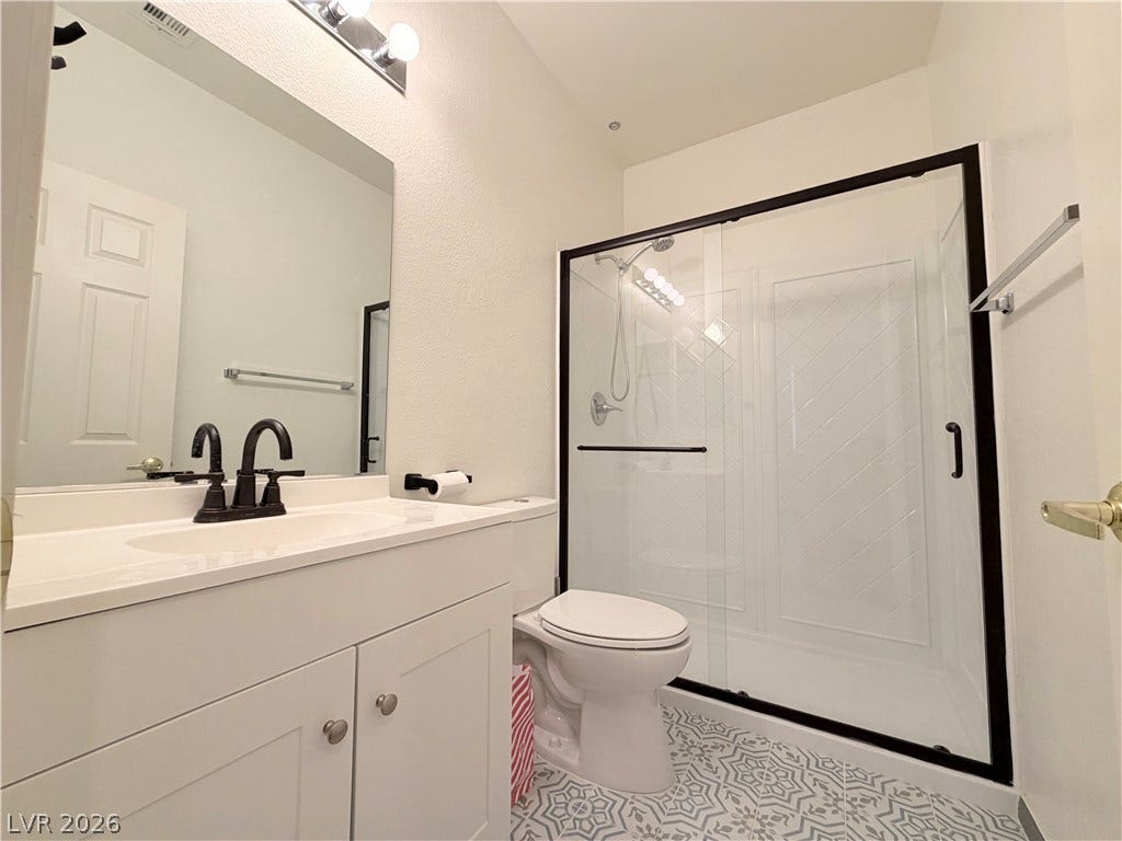 10221 Deerfield Beach Avenue, #202, Las Vegas, NV 89129 A single vanity and walk-in shower with sliding glass doors highlight this modern bathroom.