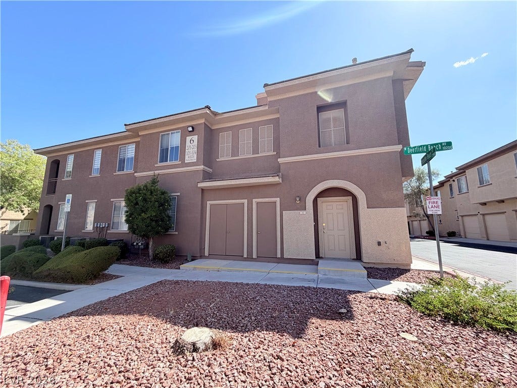 10221 Deerfield Beach Avenue, #202, Las Vegas, NV 89129 Multi-level modern stucco exterior showcases architectural arches and neat rock landscaping under clear blue skies.