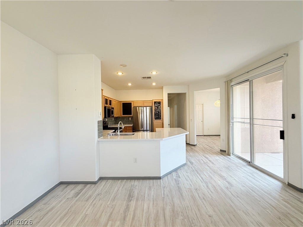 10221 Deerfield Beach Avenue, #202, Las Vegas, NV 89129 Sliding glass doors open to a private balcony, filling the open living space with natural light.