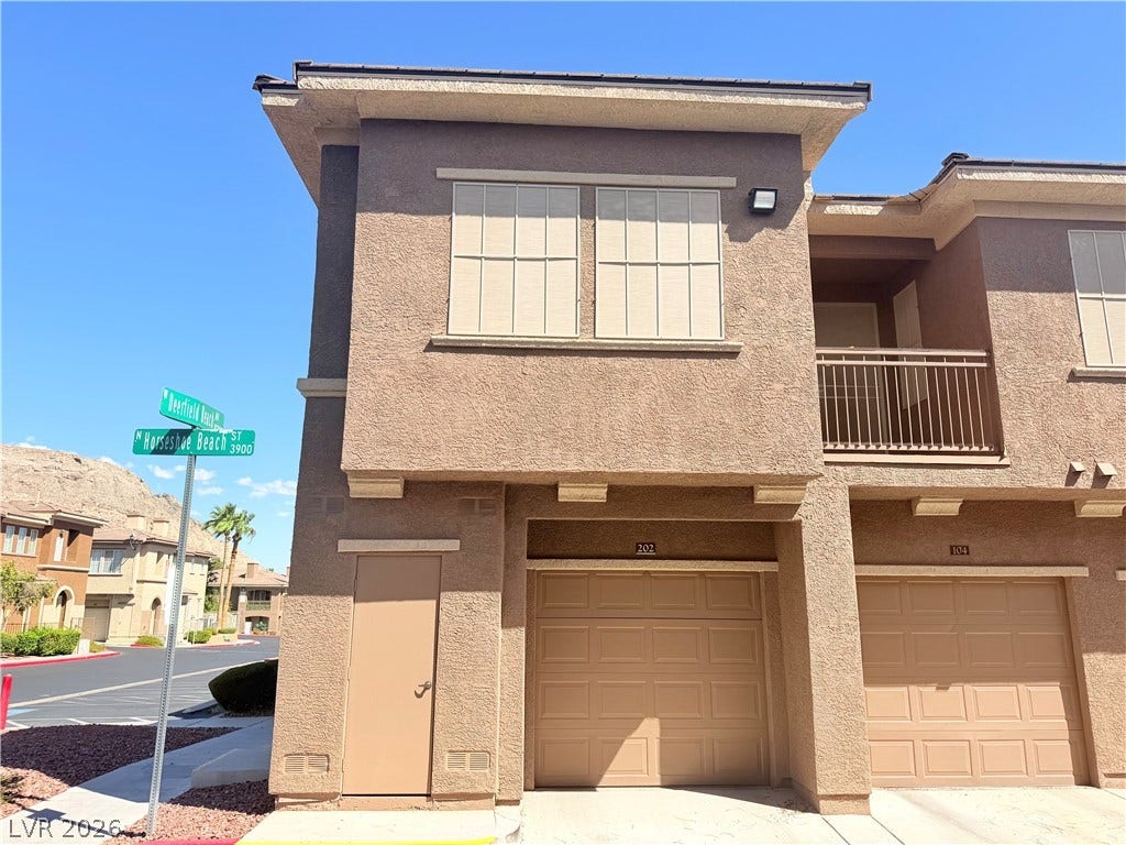 10221 Deerfield Beach Avenue, #202, Las Vegas, NV 89129 Multi-level stucco townhouse featuring attached garages and private balcony spaces.