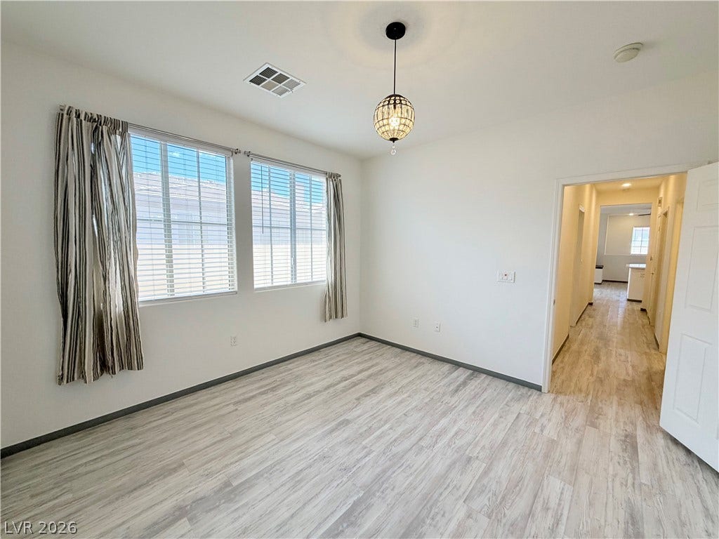 10221 Deerfield Beach Avenue, #202, Las Vegas, NV 89129 Gleaming wood-look floors anchor a sunlit room featuring multi-pane windows and neutral walls.