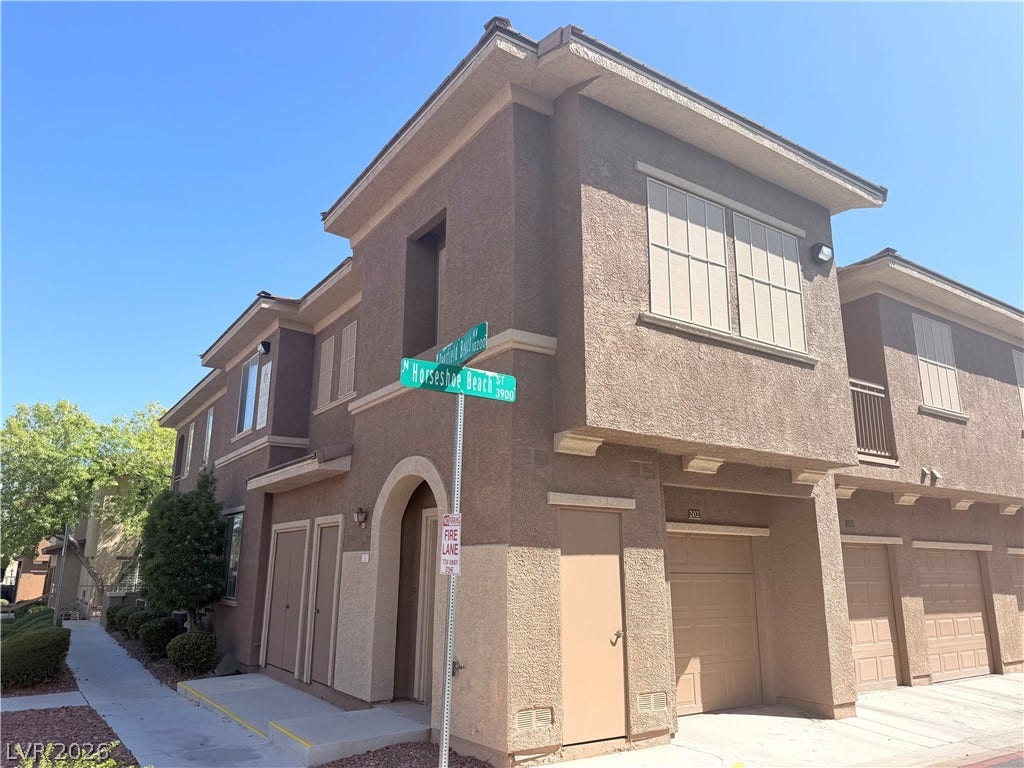 10221 Deerfield Beach Avenue, #202, Las Vegas, NV 89129 Multi-level stucco townhouse architecture features integrated garage parking and clean structural lines.