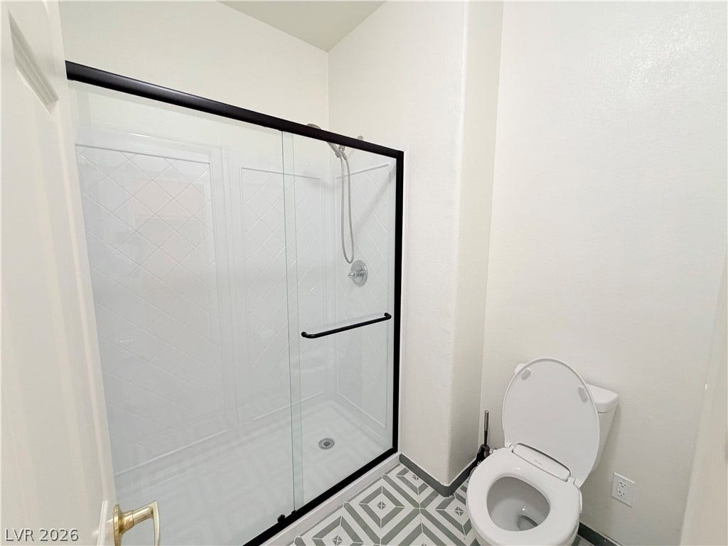 10221 Deerfield Beach Avenue, #202, Las Vegas, NV 89129 A modern glass-enclosed walk-in shower highlights this bathroom with patterned tile flooring.