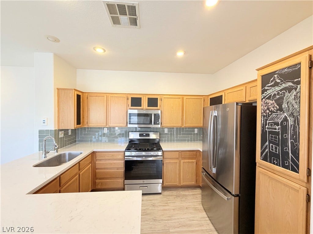 10221 Deerfield Beach Avenue, #202, Las Vegas, NV 89129 Gleaming stone countertops and classic wood cabinetry define this inviting culinary space.
