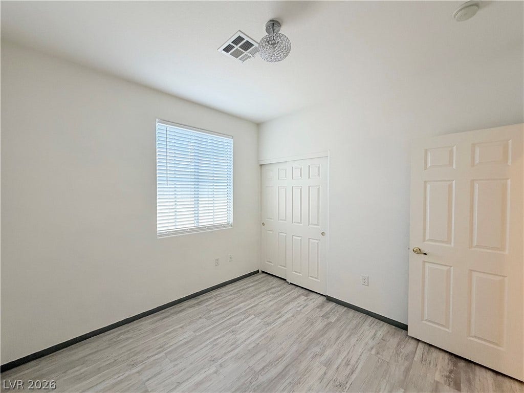 10221 Deerfield Beach Avenue, #202, Las Vegas, NV 89129 Gleaming wood-look floors and clean modern walls define this comfortable secondary bedroom.