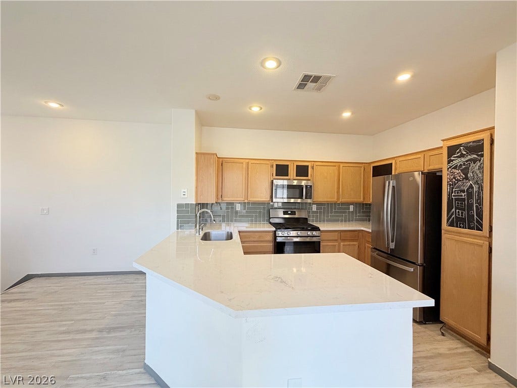 10221 Deerfield Beach Avenue, #202, Las Vegas, NV 89129 Ample stone counter space defines this modern kitchen featuring recess lighting and wood floors.