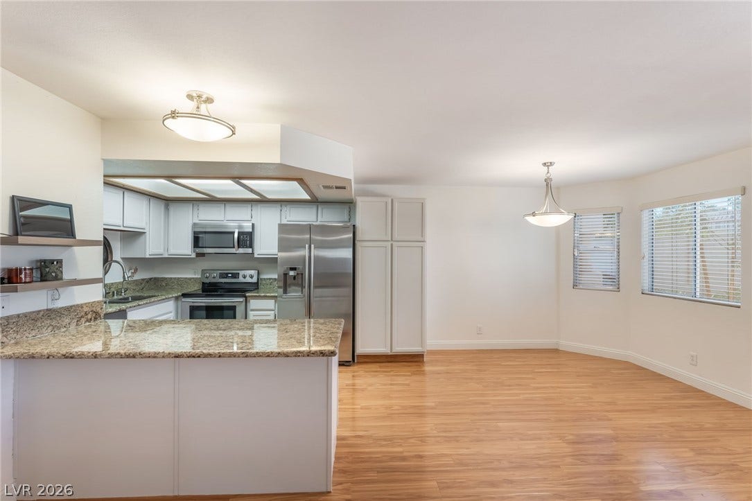 1305 Markwood Circle, #102, Las Vegas, NV 89128 Kitchen featuring light stone countertops, stainless steel appliances, light wood-style floors, a peninsula, and white cabinetry
