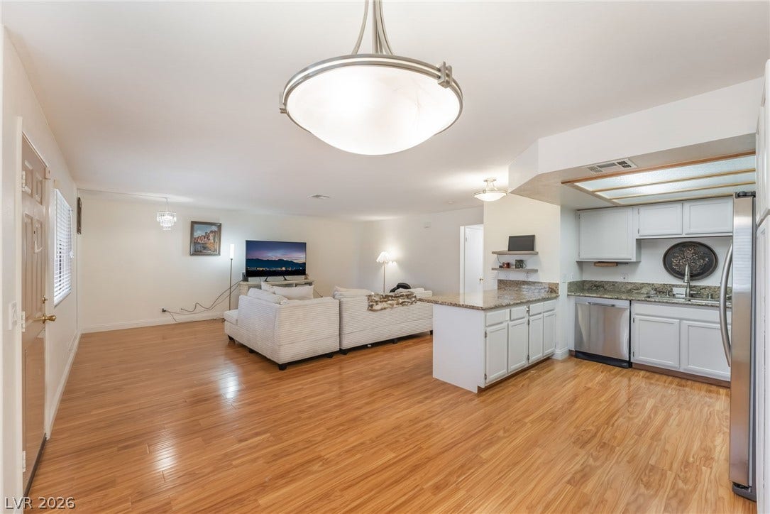 1305 Markwood Circle, #102, Las Vegas, NV 89128 Kitchen featuring open floor plan, a peninsula, stainless steel appliances, white cabinetry, and light wood-style floors