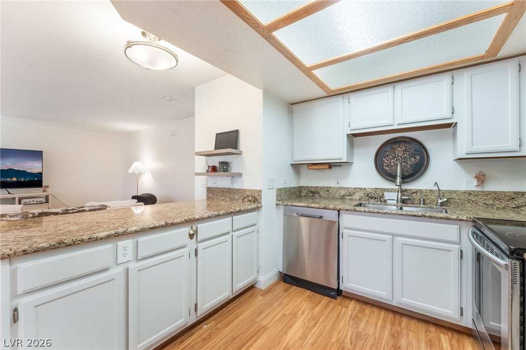 1305 Markwood Circle, #102, Las Vegas, NV 89128 Kitchen with stainless steel appliances, light stone countertops, light wood-type flooring, and white cabinets