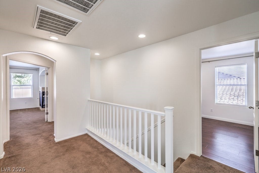 8132 Pink Desert Street, North Las Vegas, NV 89085 A well-lit landing features recessed lighting, fresh white walls, and warm carpet leading to various rooms.