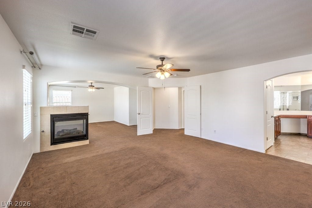 8132 Pink Desert Street, North Las Vegas, NV 89085 A spacious living room features warm carpeting, a cozy fireplace, and direct access to an adjacent area.