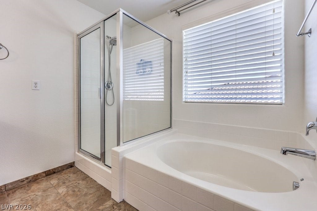 8132 Pink Desert Street, North Las Vegas, NV 89085 Indulge in this well-appointed bathroom featuring a spacious soaking tub and a sleek glass-enclosed shower.