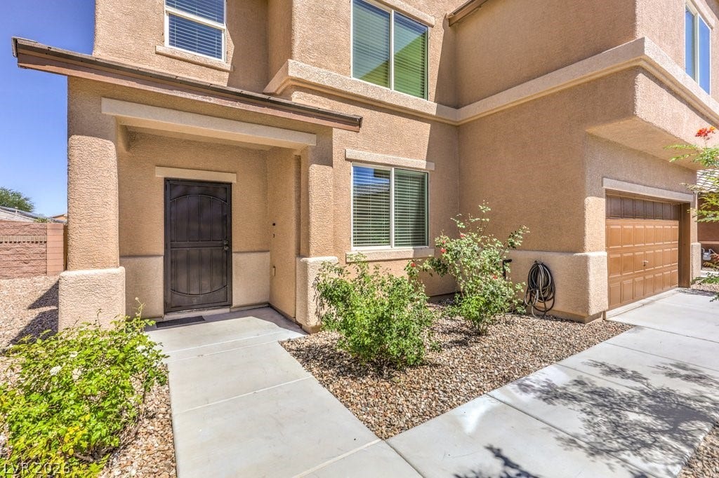 8132 Pink Desert Street, North Las Vegas, NV 89085 A welcoming front entrance with beautiful rose bushes, an attached garage, and a sturdy screen entry door.
