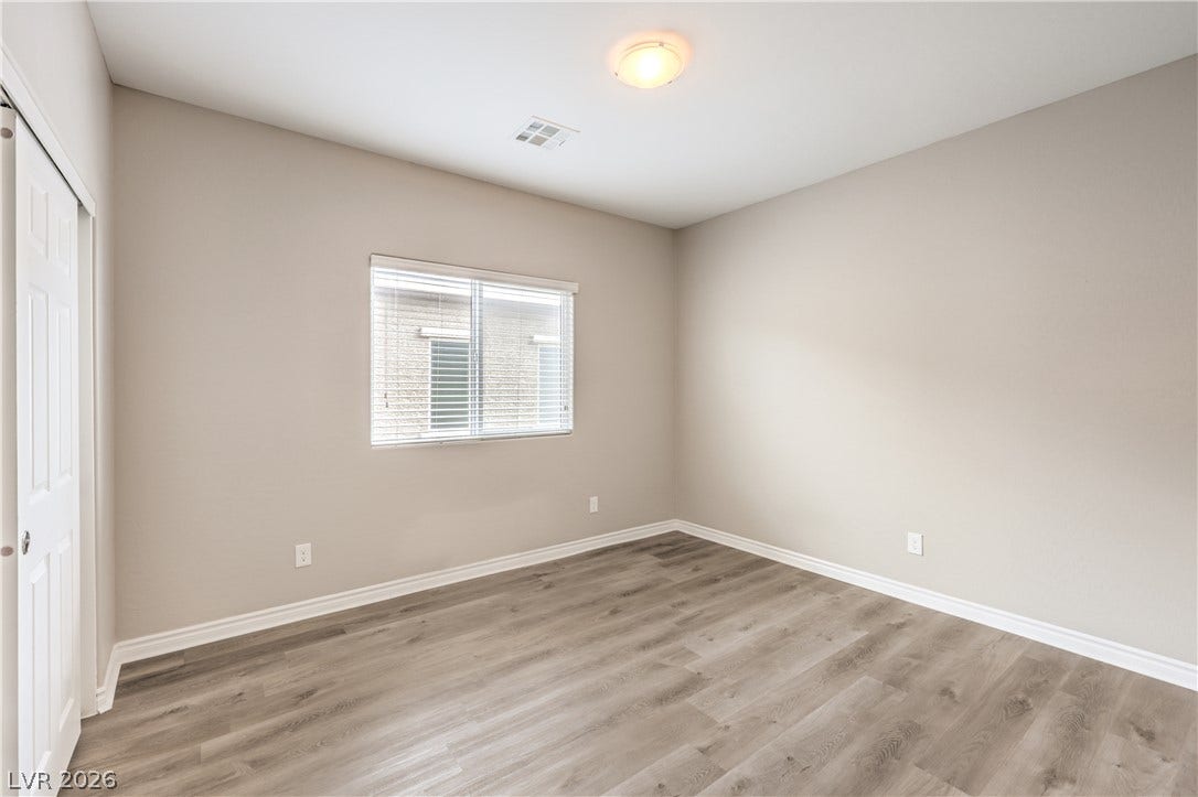 6934 Denio Island Street, North Las Vegas, NV 89084 Smooth wood-style flooring and a wide window with integrated blinds create a serene retreat in this 3rd bedroom