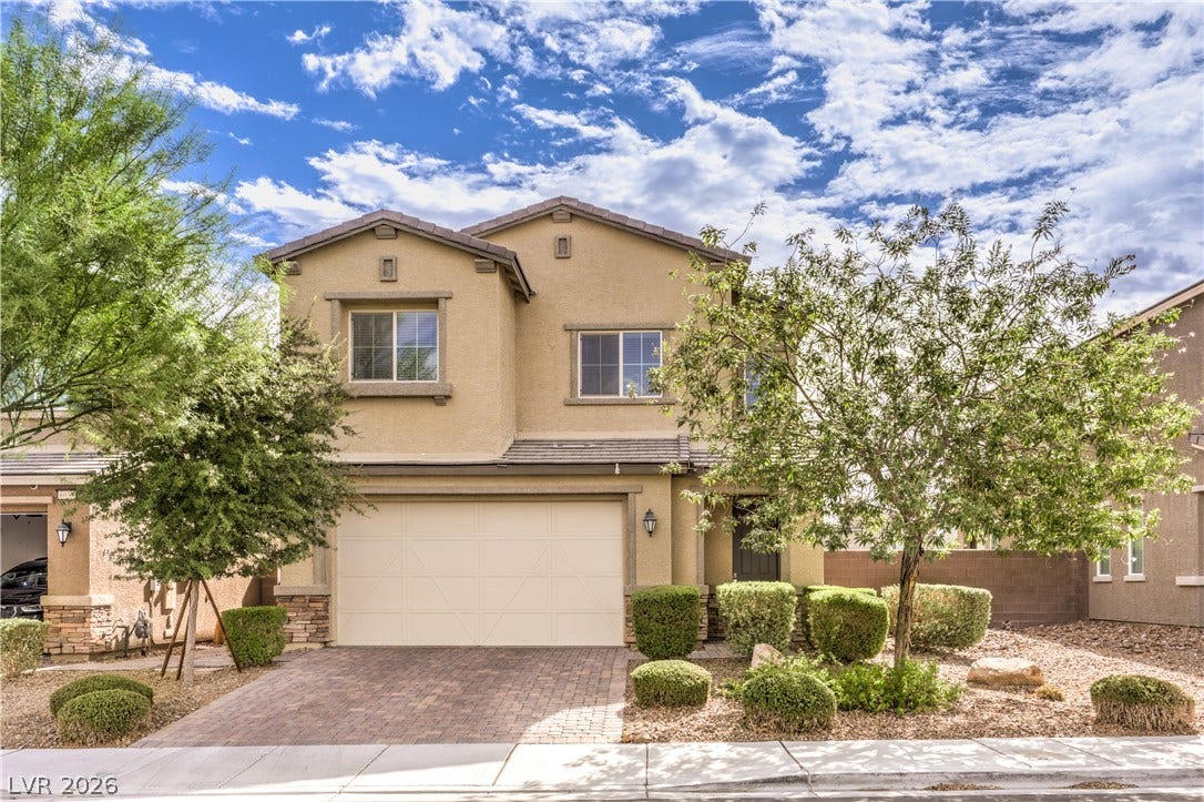6934 Denio Island Street, North Las Vegas, NV 89084 An inviting two-story stucco exterior features a paver driveway and manicured desert landscaping.