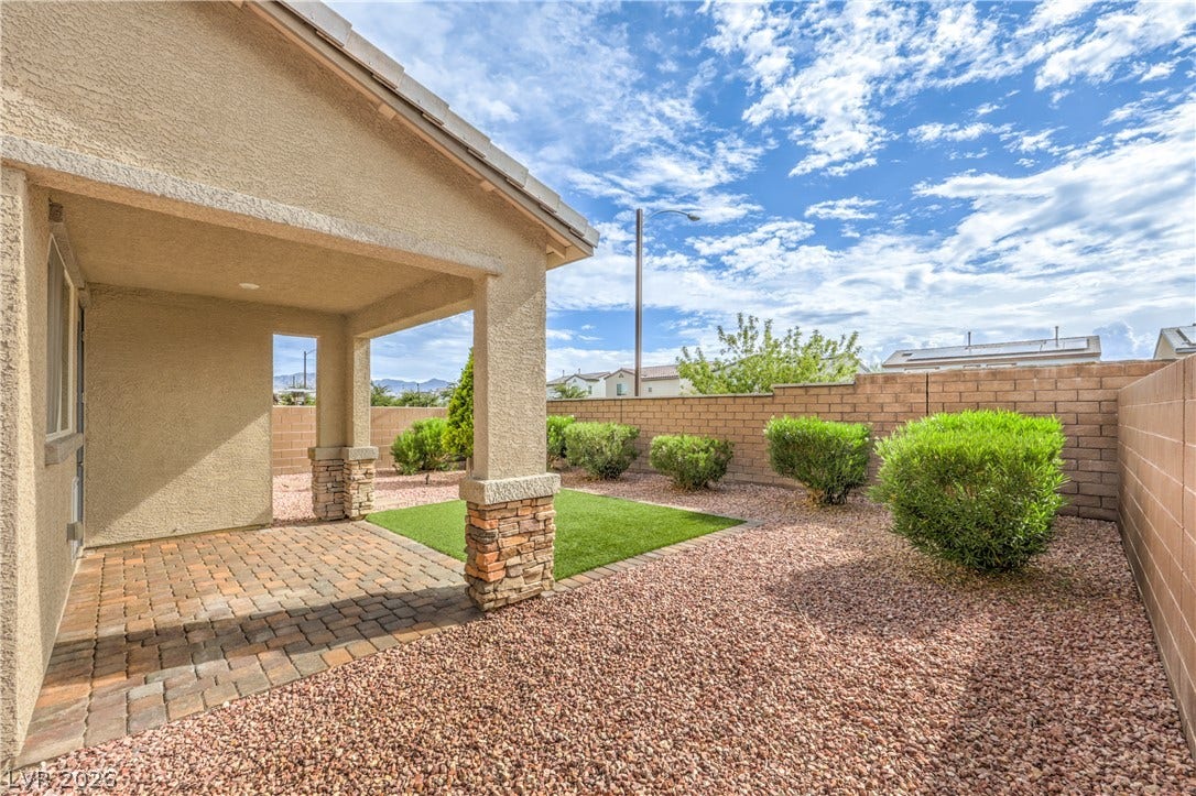 6934 Denio Island Street, North Las Vegas, NV 89084 A covered brick patio overlooks a low-maintenance gravel backyard with artificial turf.