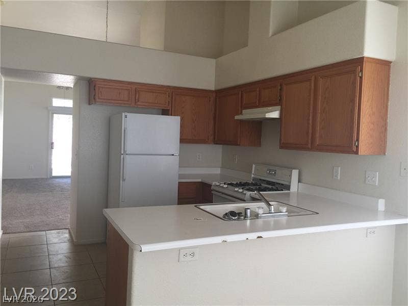 Functional kitchen design integrates with adjacent living spaces under dramatic high ceilings.