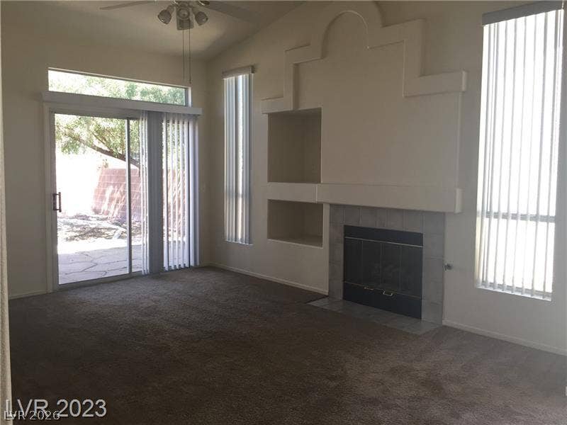 A classic fireplace accentuates this carpeted living room with sliding doors opening to the patio.