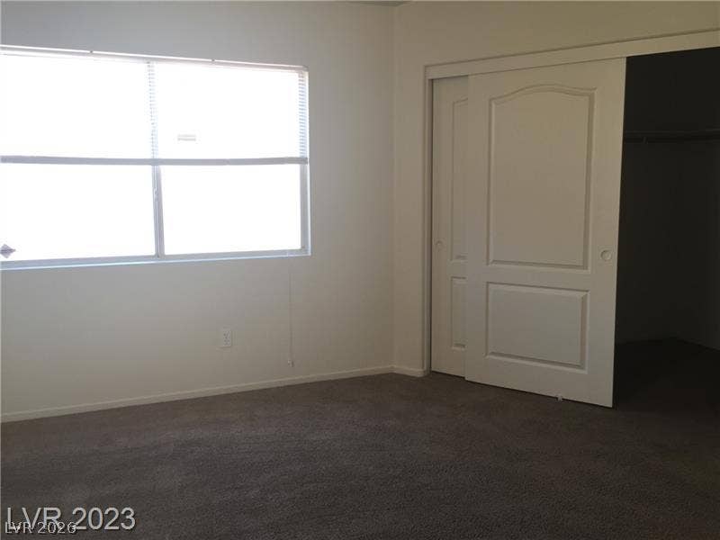 A spacious bedroom features plush carpeting and a wide window that draws in natural light.