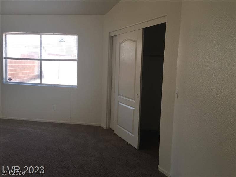 Plush carpeting and natural light define this versatile bedroom space featuring a sliding closet door.