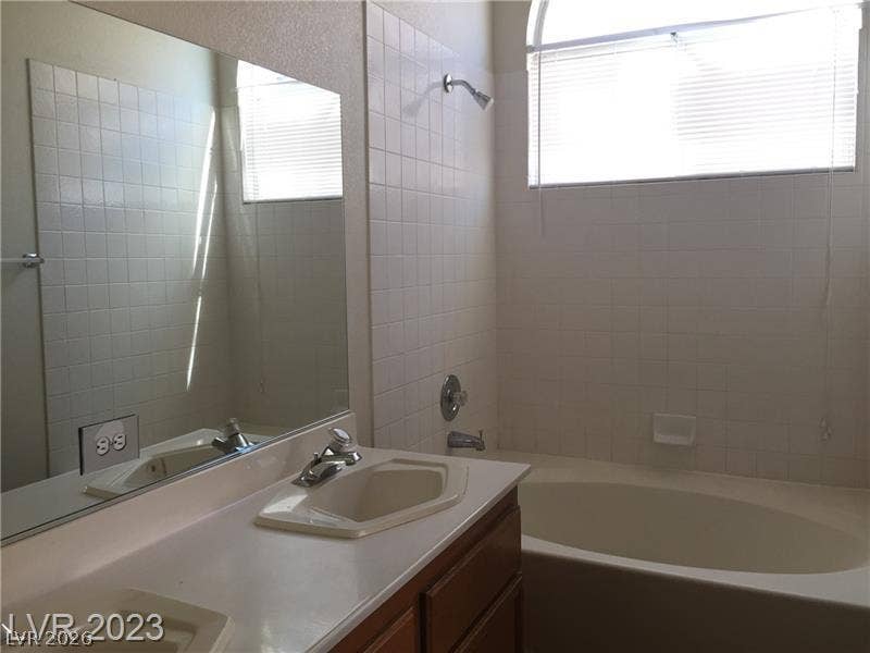 A spacious soaking tub highlights this bathroom featuring classic tiled walls and a double vanity.