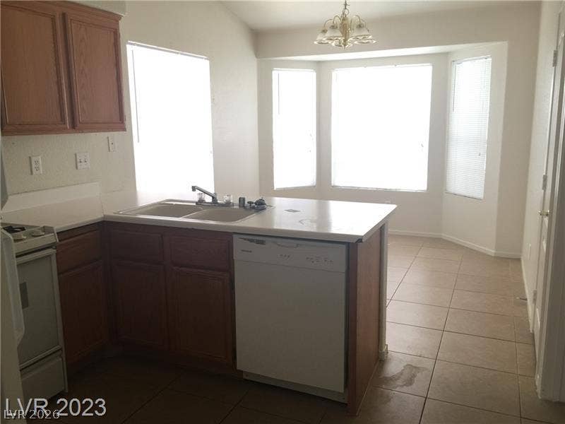 An open kitchen layout features tile flooring and natural light from a bay window.