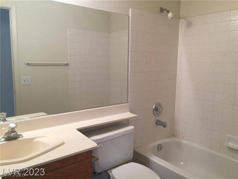 Tiled shower surround and integrated vanity sink define this functional bathroom layout.