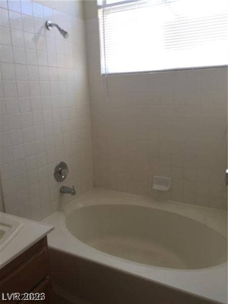 A deep soaking tub sits beneath a bright window in this bathroom.